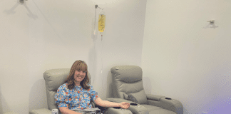 woman sits in chair receiving IV therapy