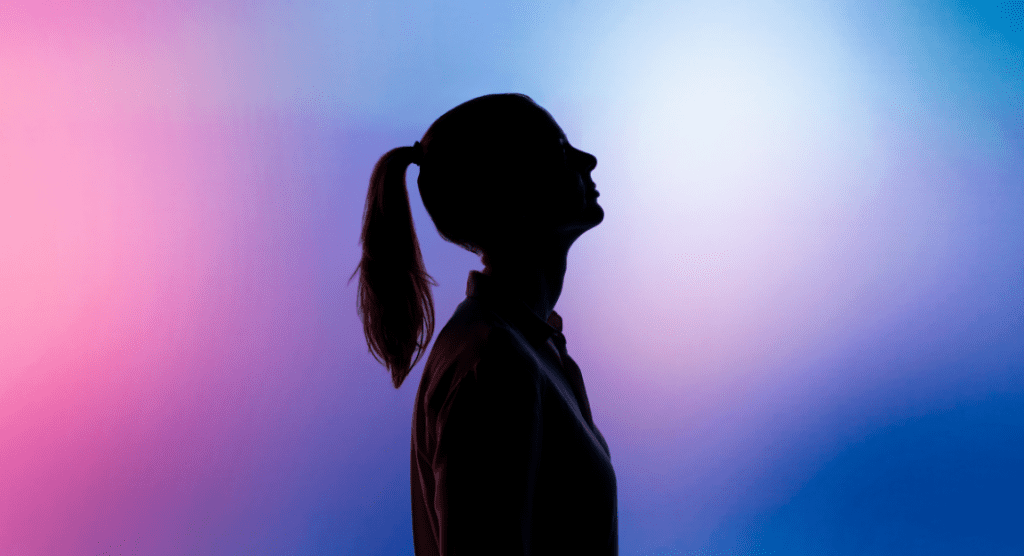 silhouette of woman with ponytail on a blue and pink background