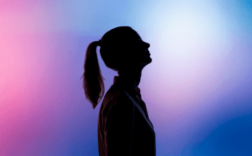 silhouette of woman with ponytail on a blue and pink background