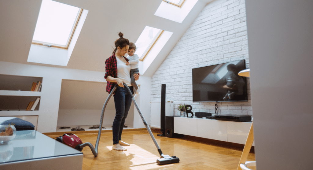woman holding toddler vacuums floor
