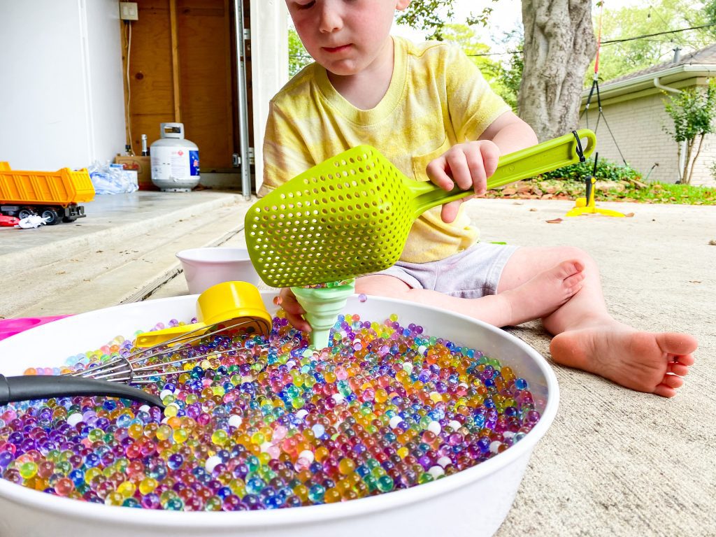 Child scoops up bubble beads from water