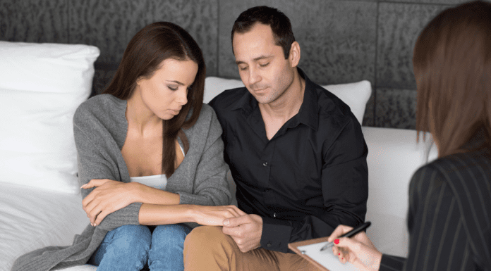 man and woman in couples therapy hold hands on therapists couch