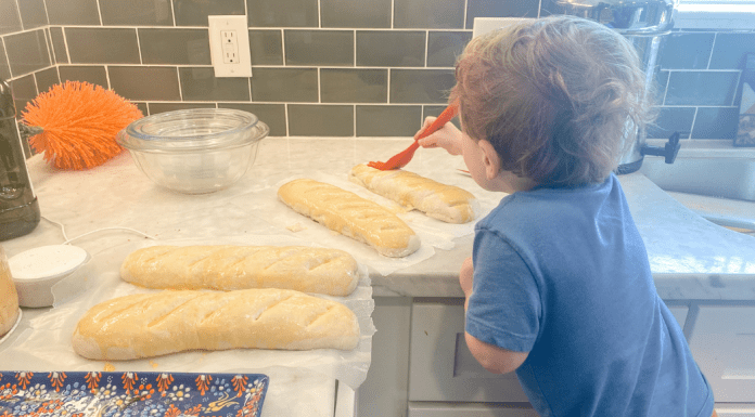 toddler buttering bread on counter