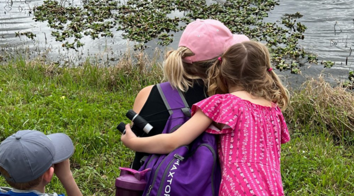 daughter embraces mother beside a lake