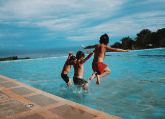 boys holding hand jumping in pool