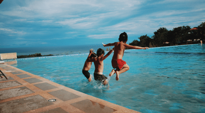 boys holding hand jumping in pool