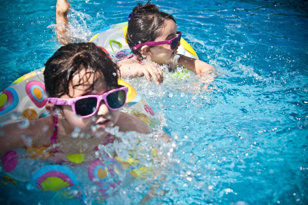 toddlers in sunglasses float in pool