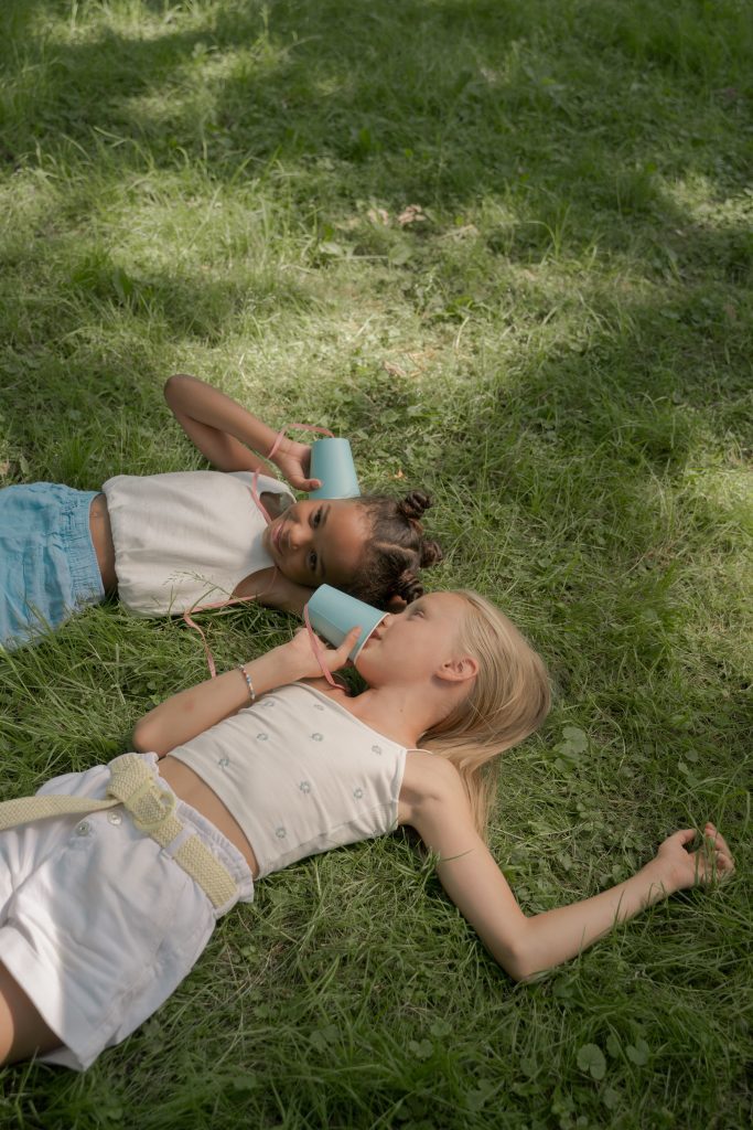 children have lazy summer laying in grass holding cups