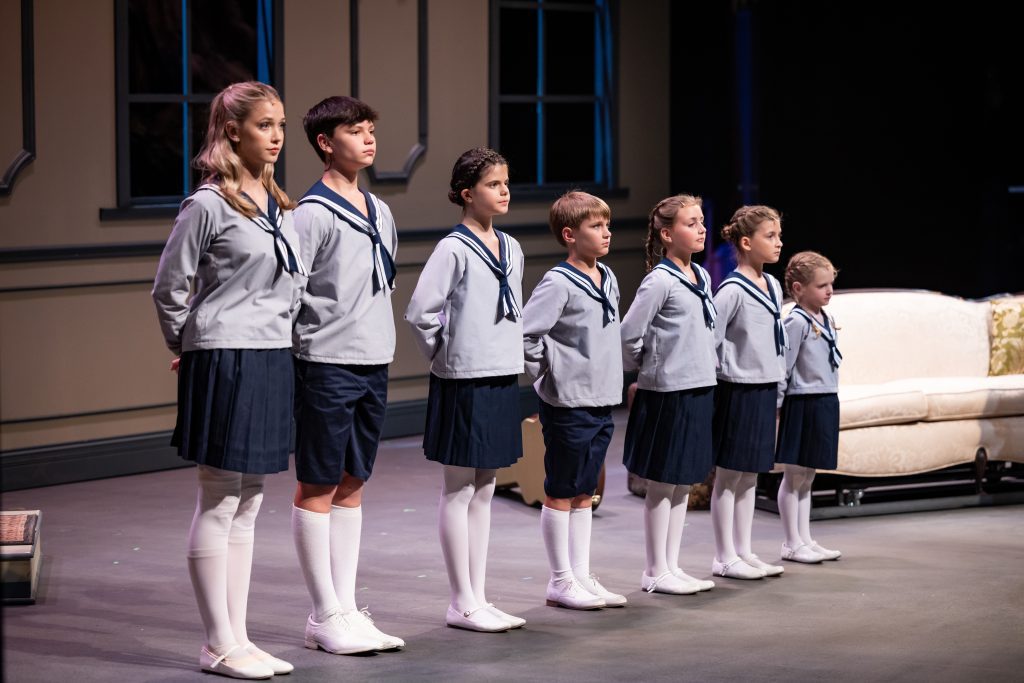 Children from The Sound of Music stand in a line in matching clothes