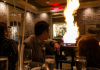 family sits at restaurant table looking at flame behind them