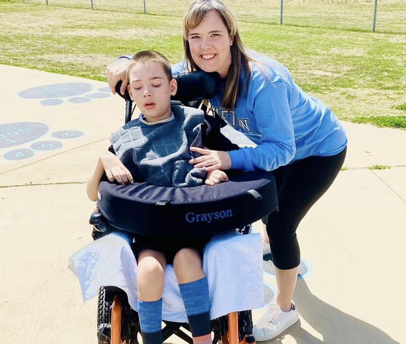 woman with arm around her son who sits in a wheelchair