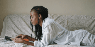 woman laying on bed reading book