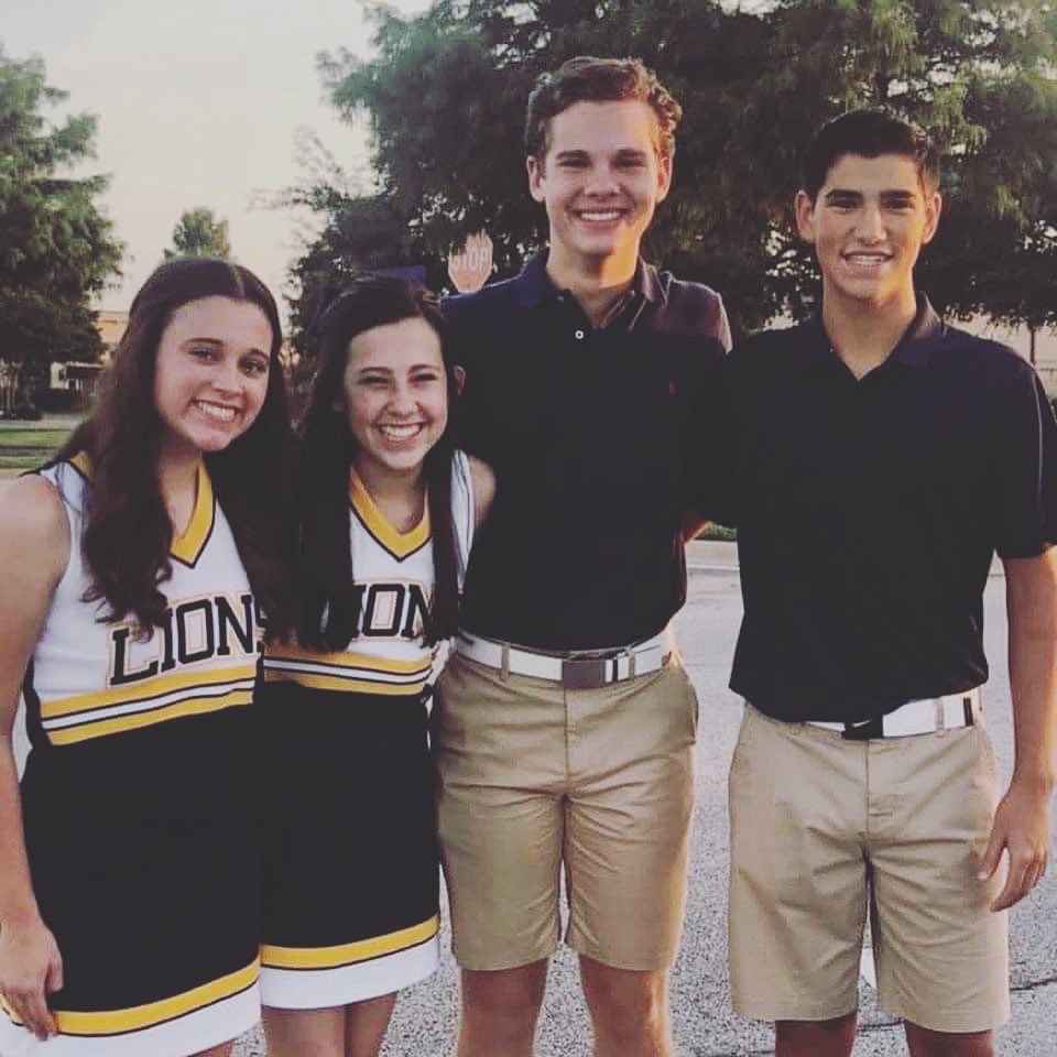 Two high school boys in school uniforms and two girls in cheerleading uniforms