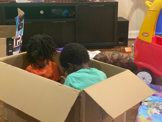 young kids sit inside cardboard box