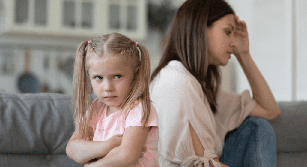 little girl with arms crossed turns back on exhausted mother