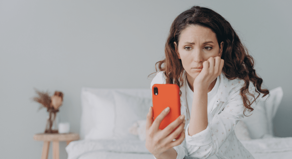 woman feeling pressure to post on social media stares at phone