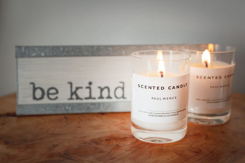 candles burning in front of sign that says Be Kind
