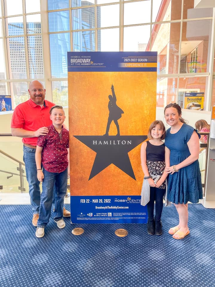 Family of four in front of Hamilton sign at Hobby Center