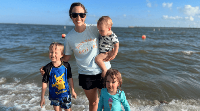 mother stands with three kids in ocean
