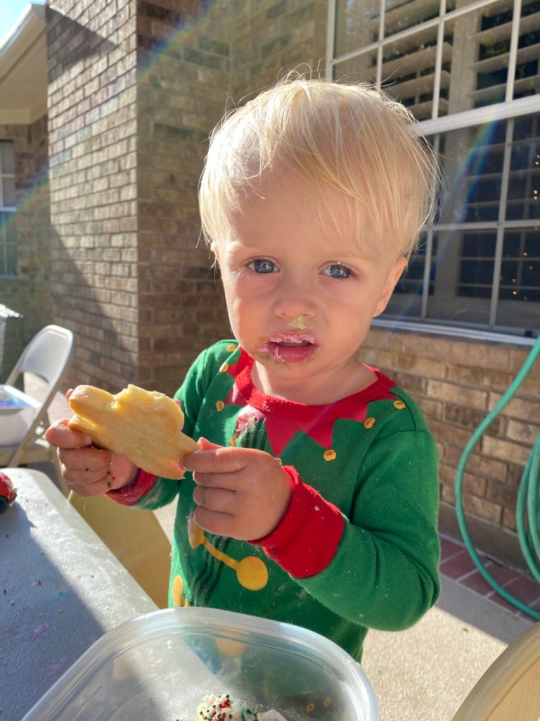 child in elf pajamas eats cookie