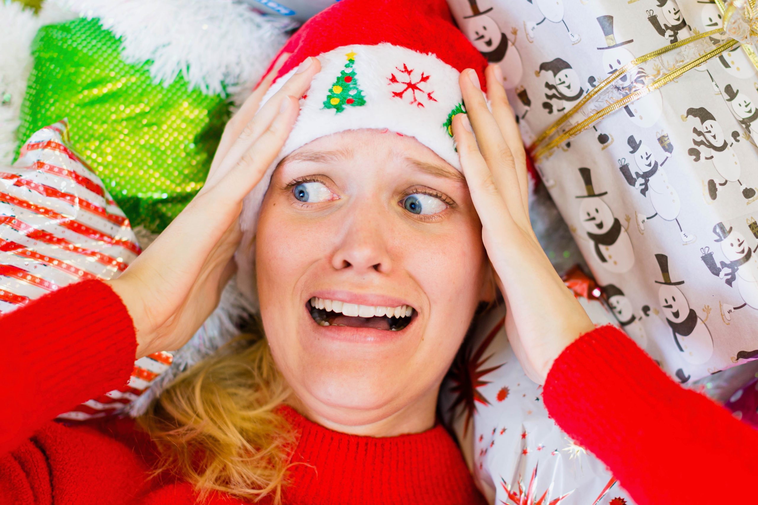 woman laying down in holiday clothes has frightened expression on her face