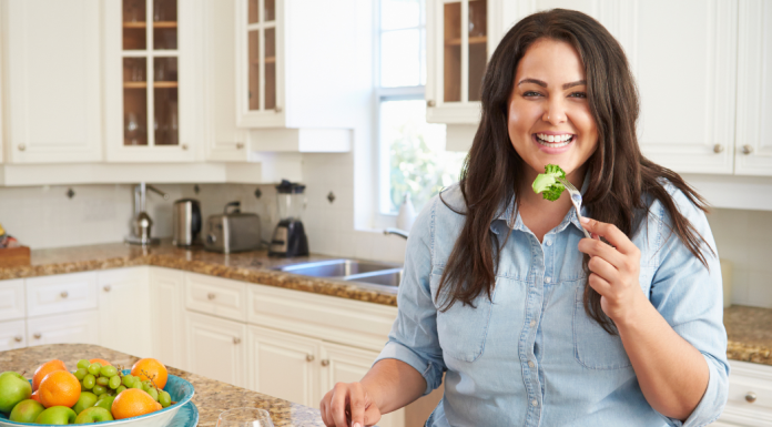 Foods to Boost Your Immune System for a Very Happy Holidays woman smiling while eating a bite of broccoli