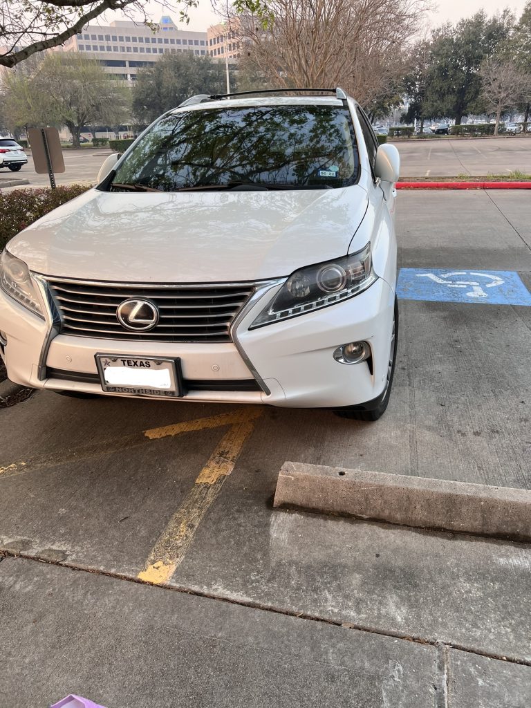 car parked over the line of a parking spot and into an accessible parking spot