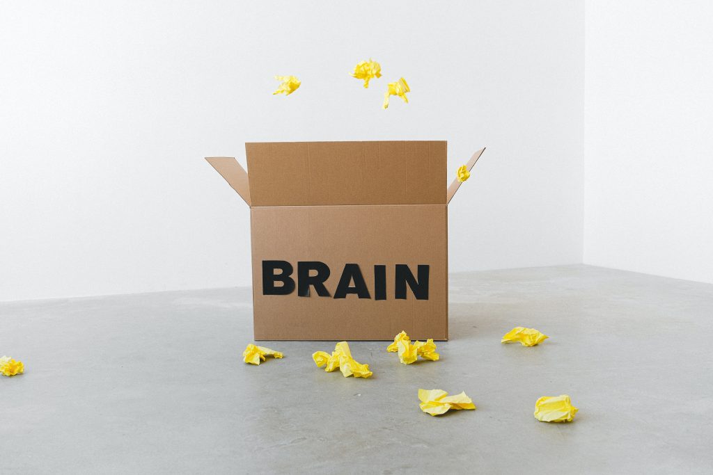 cardboard box that says "Brain" with crumpled papers all around it