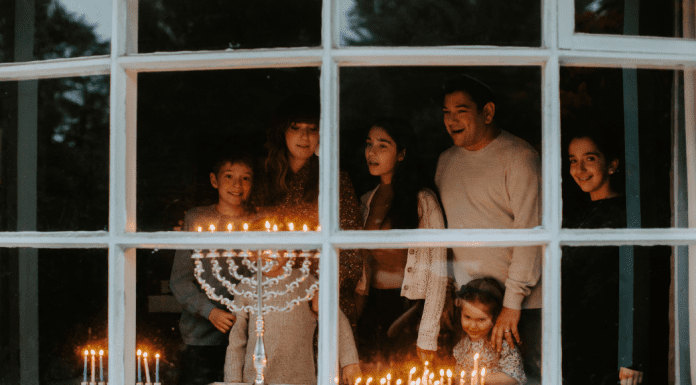 family stands in front of window looking at a Menorah