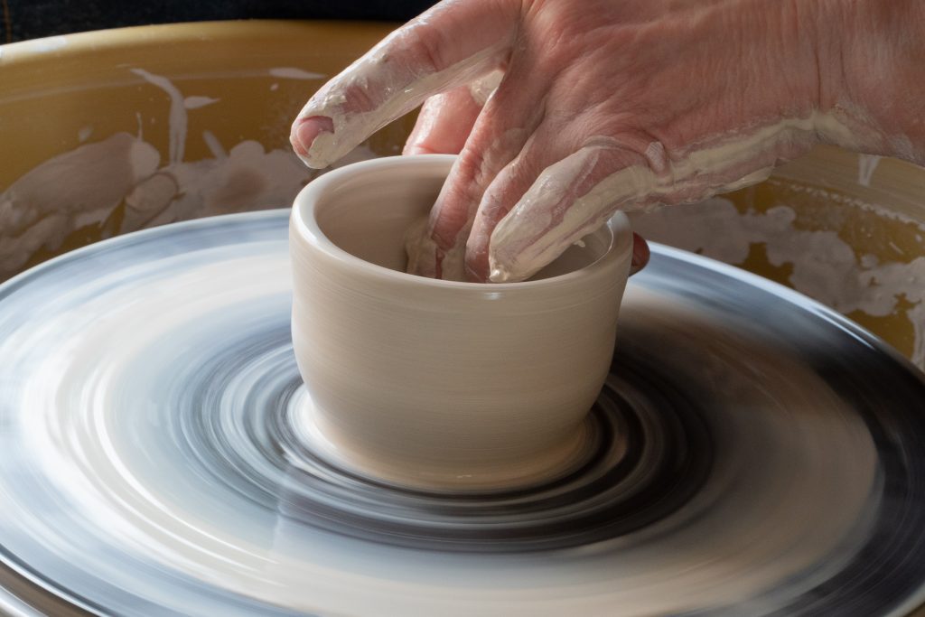hands making pottery on a wheel