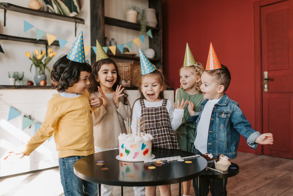 kids at birthday party gather around cake
