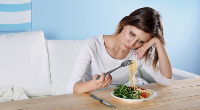 sad woman holding up a bite of spaghetti