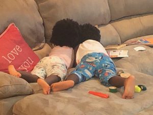 twins lay on their stomachs on the couch