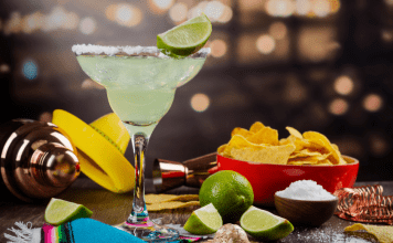 margarita, chips, limes and salt on table