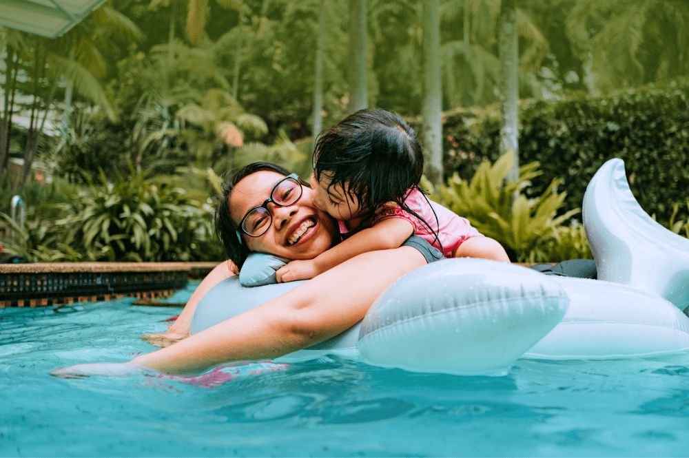 Little girl kisses mom on the cheek in a pool