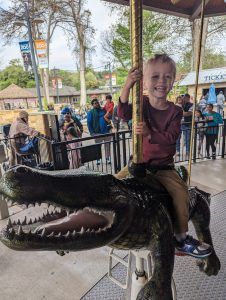 child on alligator seat on carousel