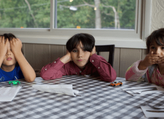 three kids suffering from summer boredom sit at kitchen table