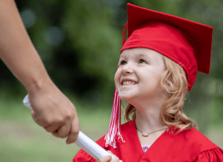 preschool girl in cap and gown accepts diploma