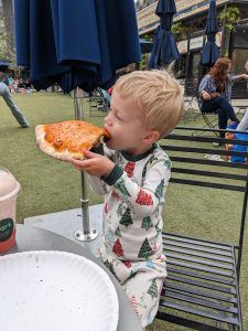toddler eating a large slice of pizza