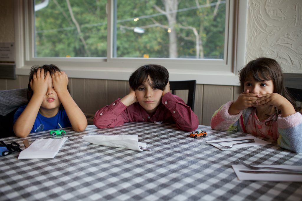 Three children sit, bored, at the kitchen table