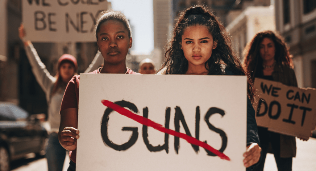 women protesting gun violence hold signs