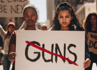 women protesting gun violence hold signs