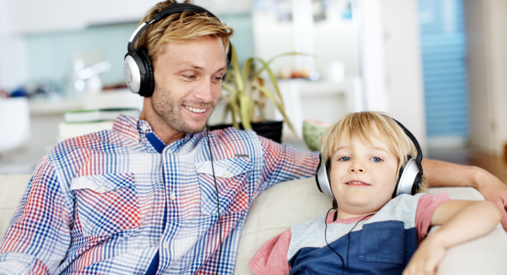 Dad and son on couch listening to music through headphones