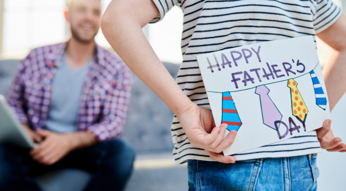 boy holds father's day card behind his back