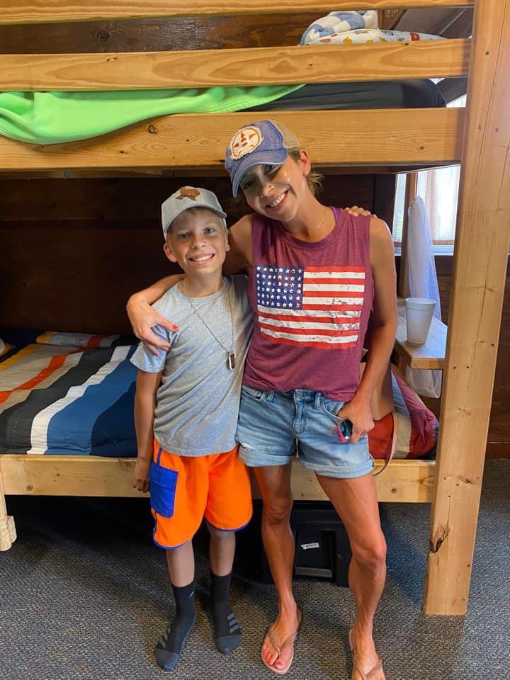 mother and son stand in front of bunk beds in camp cabin