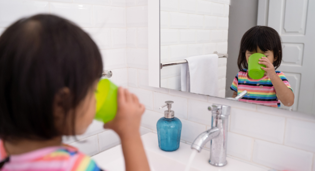 child stands in bathroom rinsing mouth 