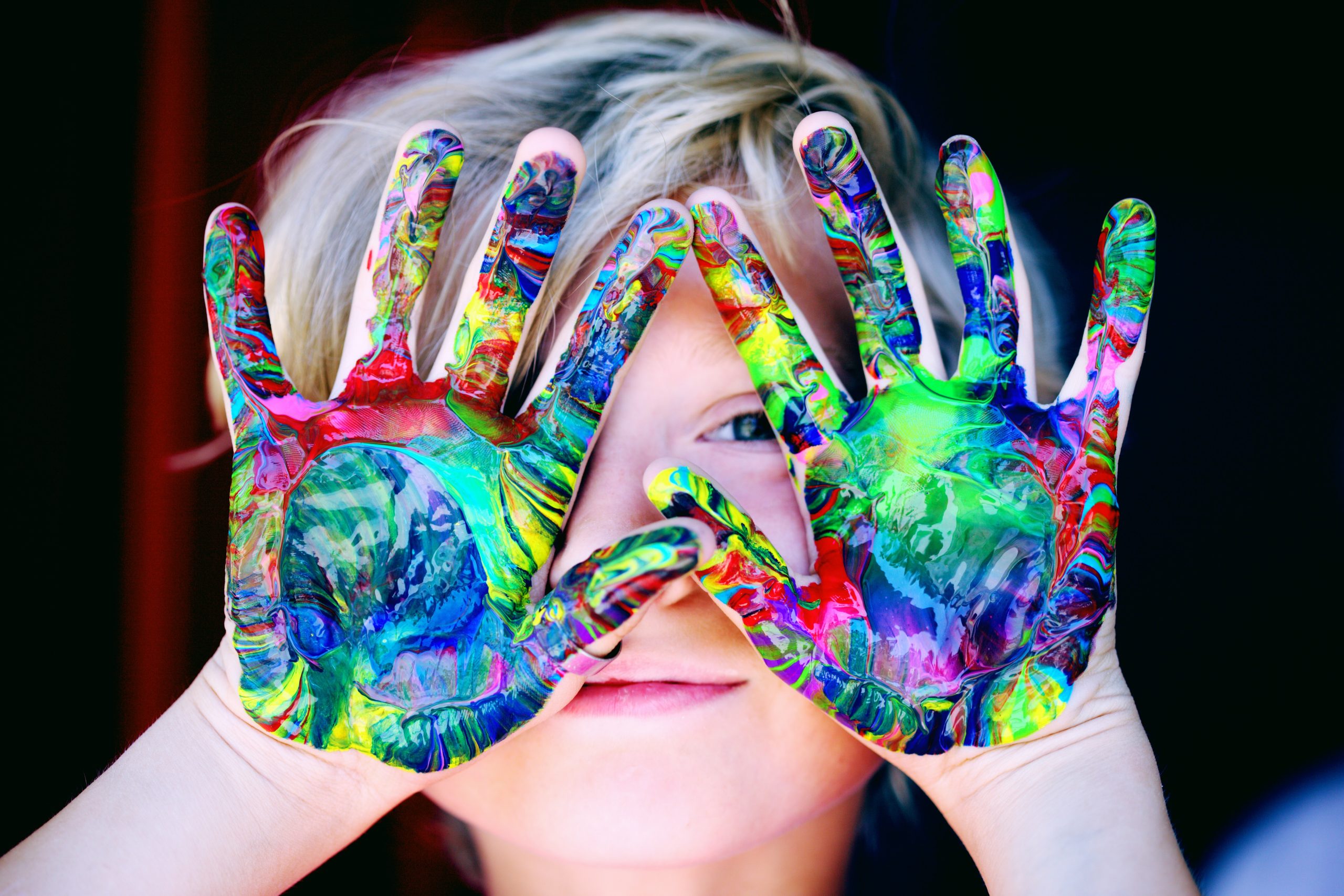 boy holding up painted hands in front of face