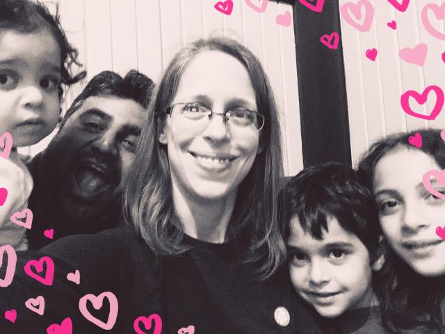family of five with pink hearts in background