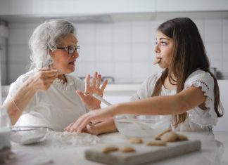 grandmother talking to granddaughter, who has a cookie in her mouth
