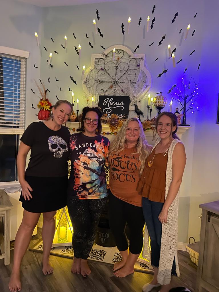 Group of women dressed in Halloween t shirts in decorated house